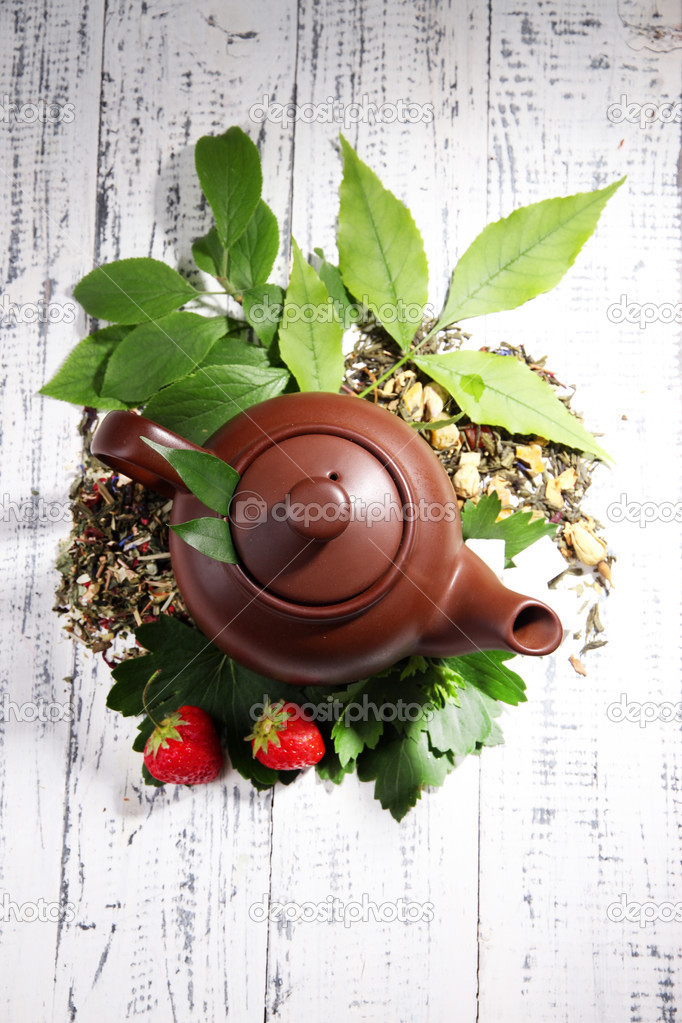 Herbal natural tea in teapot with dry flowers and herbs ingredients, on color wooden background