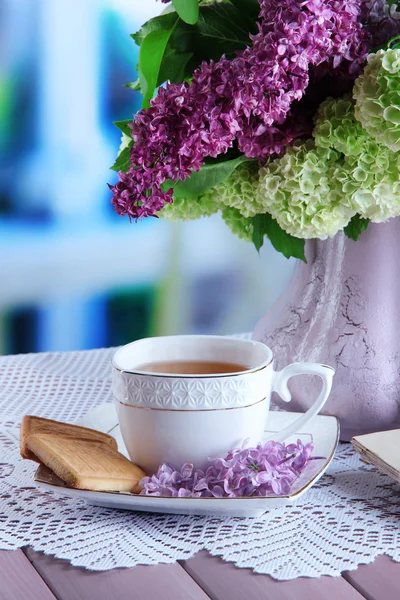Composição com xícara de chá, cartas antigas e belas flores de primavera em vaso, na mesa de madeira, no fundo brilhante — Fotografia de Stock