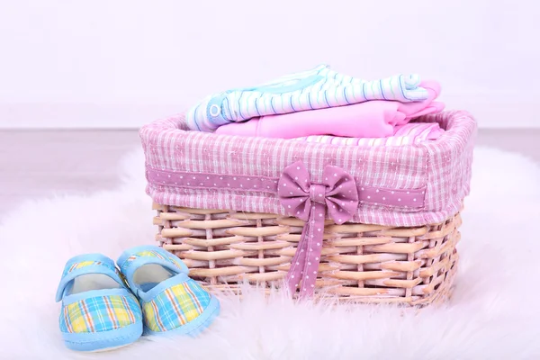 Baby clothes in basket on floor in room — Stock Photo, Image