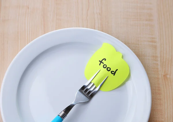 Note paper with message  attached to fork, on plate, on color wooden background — Stock Photo, Image