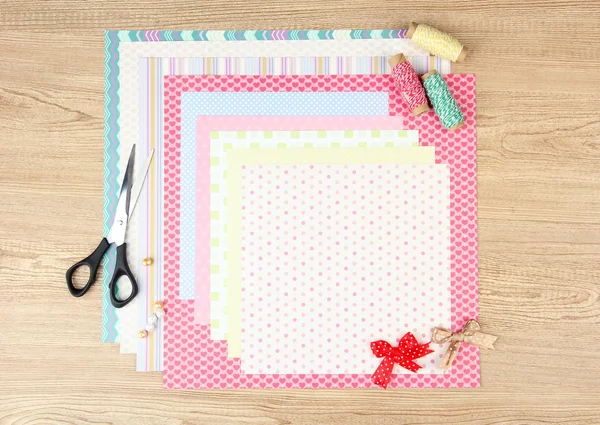 Papier voor scrapbooking en hulpmiddelen voor op houten tafel — Stockfoto