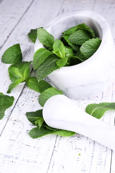 Fresh green mint in mortar on color wooden background — Stock Photo, Image