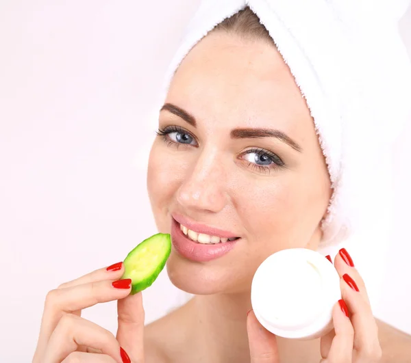 Beautiful young woman holding  fresh cucumber slices  and bowl with cream, isolated on white — Stock Photo, Image