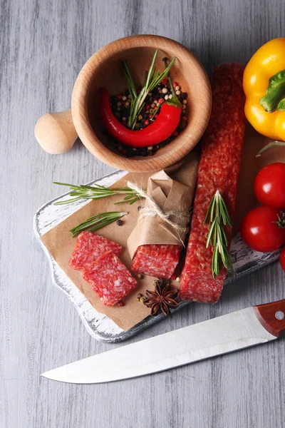 Salsiccia saporita, verdure e spezie su carta, su fondo di legno — Foto Stock