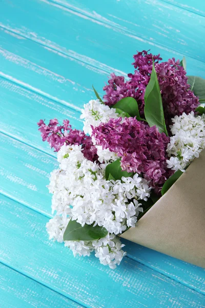 Beautiful bouquet of lilac flowers on color wooden background — Stock Photo, Image