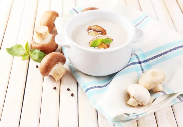 Mushroom soup in white pot, on napkin, on wooden background — Stock Photo, Image