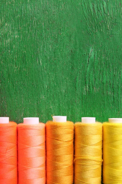 Hilos de costura multicolor sobre fondo de madera — Foto de Stock