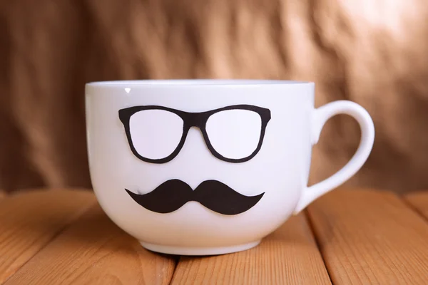 Cup with mustache on table on brown background — Stock Photo, Image