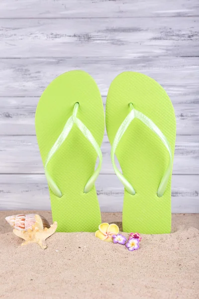 Bright flip-flops on sand, on wooden background — Stock Photo, Image