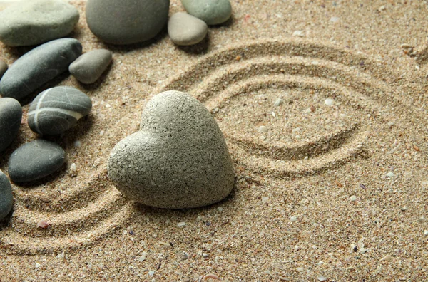 Grey zen stone in shape of heart, on sand background — Stock Photo, Image