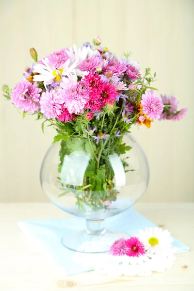 Wilde bloemen in glazen vaas op tafel op lichte achtergrond — Stockfoto