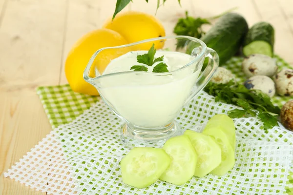 Yogurt al cetriolo in ciotola di vetro, su tovagliolo di colore, su sfondo di legno a colori — Foto Stock