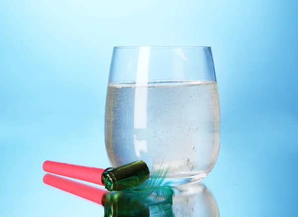Vidro com comprimido efervescente em água com bolhas sobre fundo azul — Fotografia de Stock