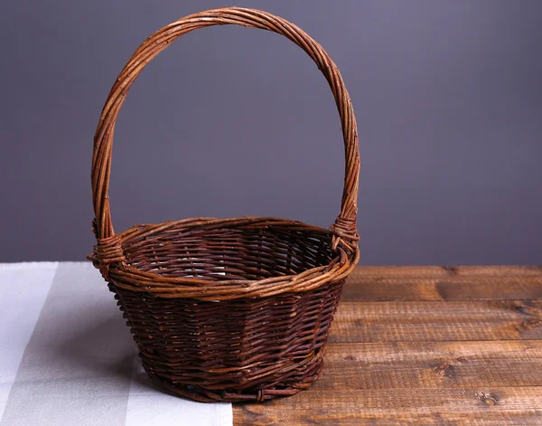 Pusty wiklinowy koszyk na drewnianym stole, na ciemnym tle — Zdjęcie stockowe
