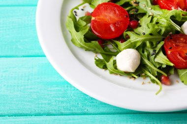 roka, domates, peynir mozzarella toplar ve plaka renk ahşap zemin üzerine susam ile yapılan yeşil salata
