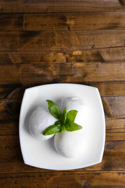 Sabroso queso mozzarella con albahaca en plato sobre fondo de madera —  Fotos de Stock