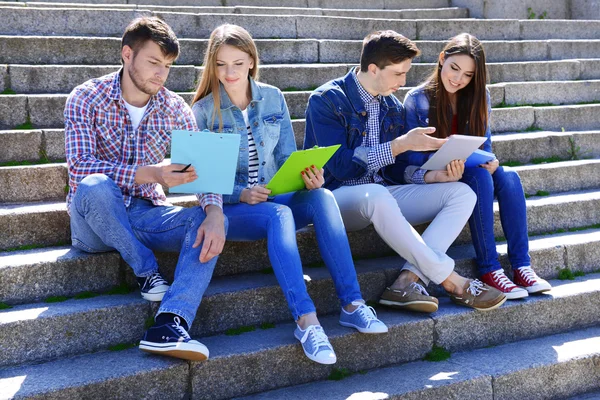 Estudiantes felices sentados en escaleras en el parque — Foto de Stock