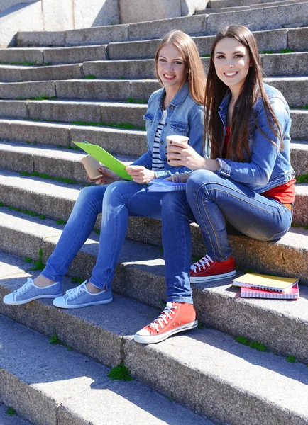 Šťastní studenti sedí na schodech v parku — Stock fotografie