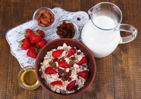 Gezonde ontbijtgranen met melk en aardbei op houten tafel — Stockfoto