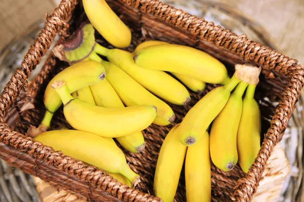 Ramo de mini plátanos en caja de mimbre sobre fondo de saco —  Fotos de Stock