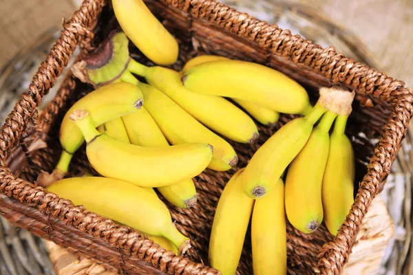 Bando de mini bananas em caixa de vime em fundo de pano de saco — Fotografia de Stock