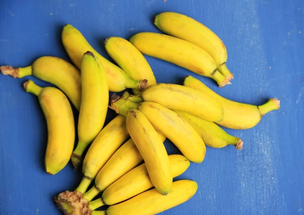 Bunch of mini bananas on color wooden background — Stock Photo, Image