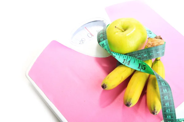 Bos van mini bananen en meetband op schalen, geïsoleerd op wit — Stockfoto