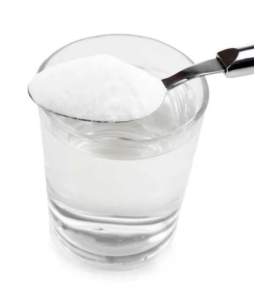 Cuchara de bicarbonato de sodio sobre un vaso de agua, aislado en blanco —  Fotos de Stock