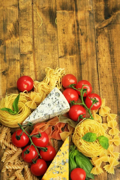 Verschiedene Nudeln, Käse und Tomaten auf Holztisch in Großaufnahme — Stockfoto