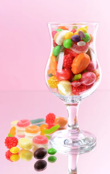 Verschiedene bunte Fruchtbonbons im Glas auf rosa Hintergrund — Stockfoto