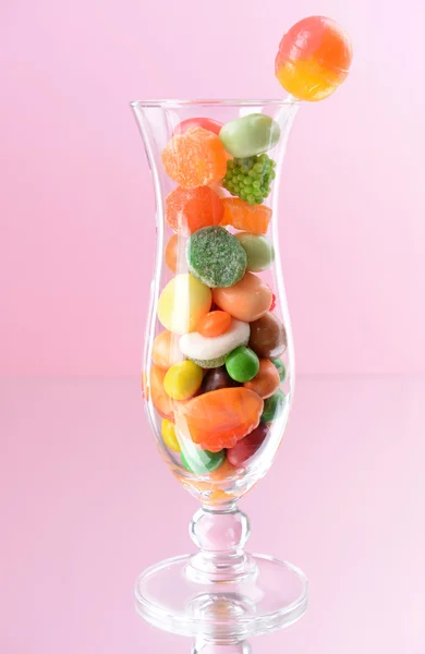 Olika färgglada frukt godis i glas på rosa bakgrund — Stockfoto