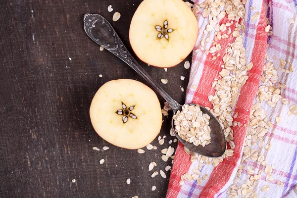 Apple with oatmeal and vintage spoons on napkin, on color wooden background — Stock Photo, Image