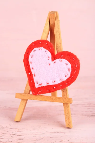 Schönes Herz kleine dekorative Staffelei auf rosa Hintergrund — Stockfoto