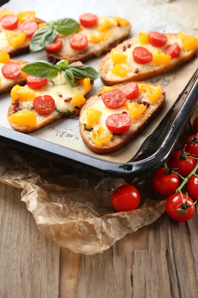 Smakelijke bruschetta met tomaten op pan, op oude houten tafel — Stockfoto