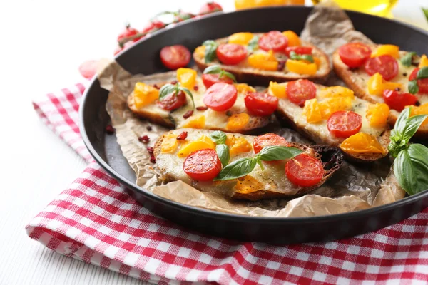 Sabroso bruschetta con tomates en la cacerola, sobre la mesa — Foto de Stock