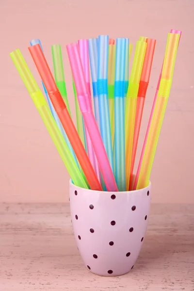 Strohhalme in Tasse auf rosa Hintergrund — Stockfoto