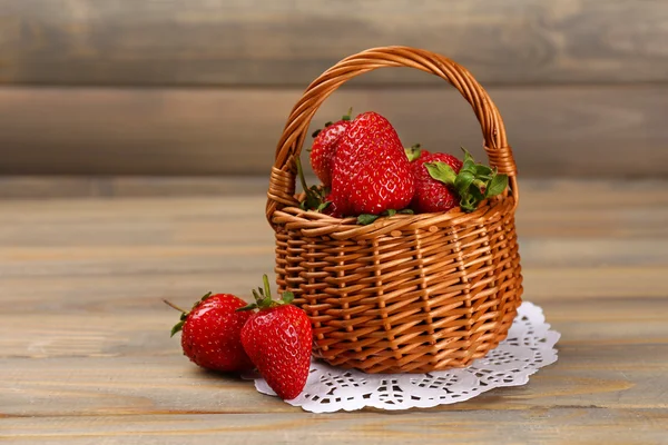 Red ripe strawberries in wicker basket on wooden background — Stock Photo, Image