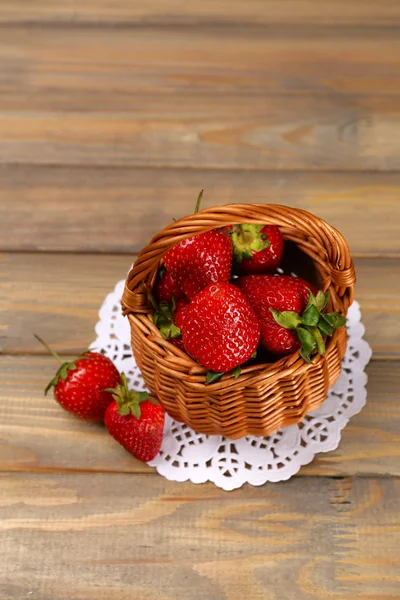 Rødmodne jordbær i flettekurv på trebakgrunn – stockfoto