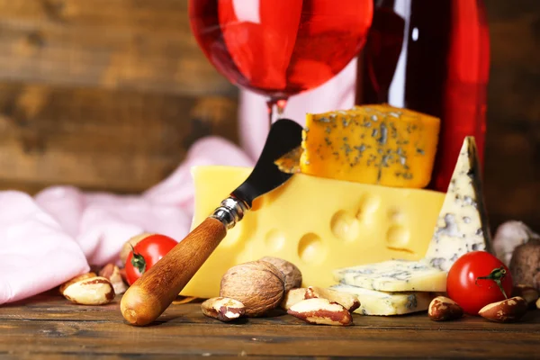 Pink wine and different kinds of cheese on wooden background — Stock Photo, Image