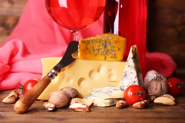 Vino rosa e diversi tipi di formaggio su sfondo tessuto — Foto Stock