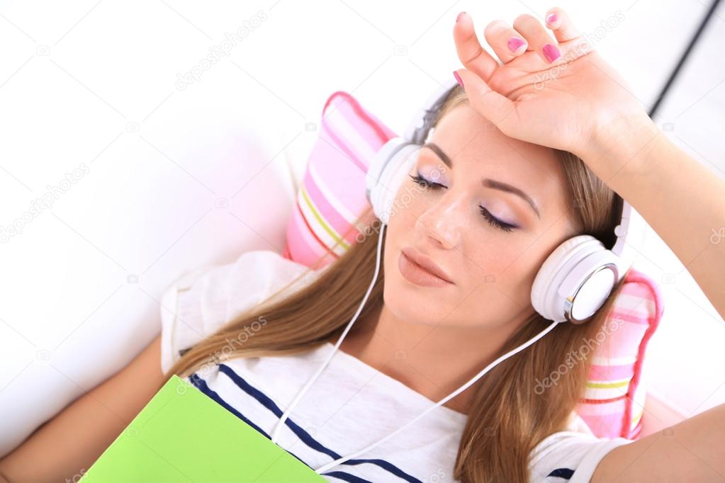 Conceptual image of  audio book. Beautiful girl with book and headphones.