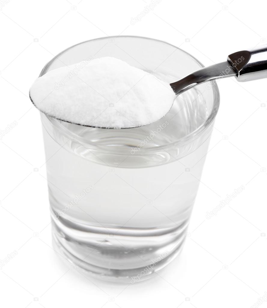Spoon of baking soda over glass of water, isolated on white