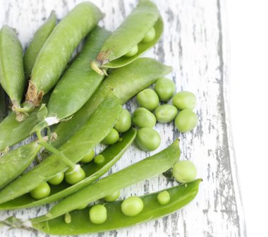 Beyaz arka plan üzerinde izole ahşap tahta üzerinde taze yeşil bezelye