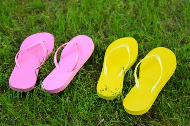 Yeşil çimenlerin üzerinde parlak parmak arası terlik 