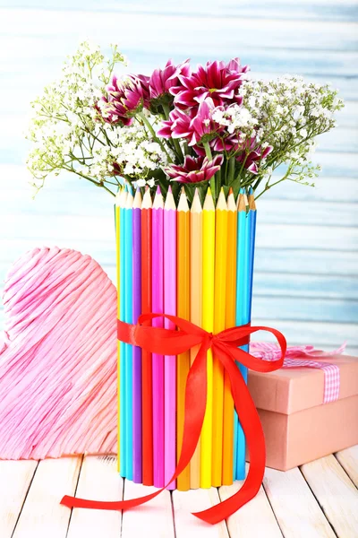 Vackra blommor i färgglada pennor vas på trä bakgrund — Stockfoto