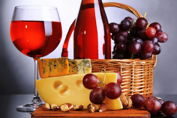 Vino rosa, uva e formaggio su fondo grigio — Foto Stock