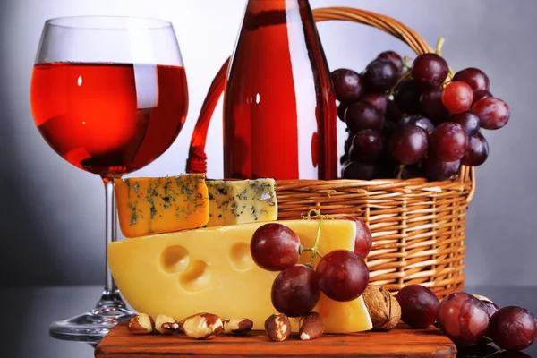 Pink wine, grapes and cheese on grey background — Stock Photo, Image