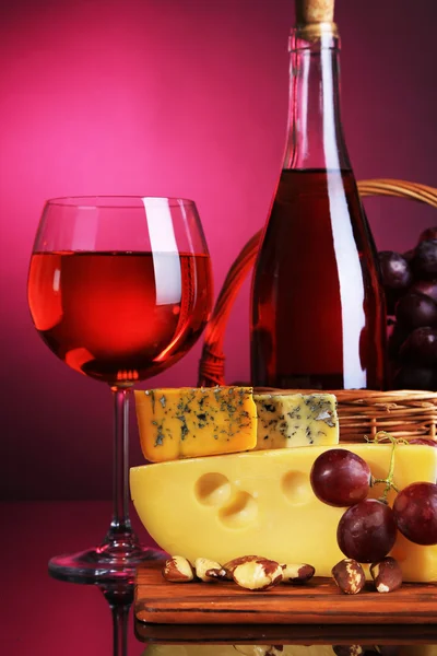 रंगीत पार्श्वभूमीवर गुलाबी वाईन, द्राक्ष आणि चीज — स्टॉक फोटो, इमेज