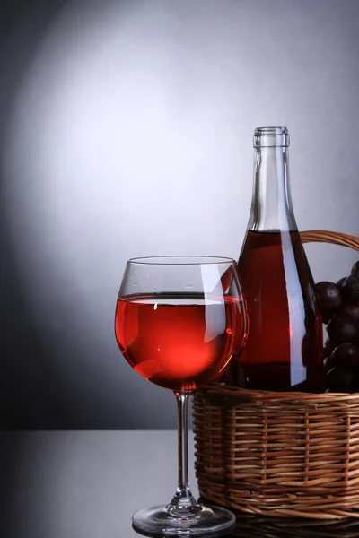 Ripe grapes, wine glass and bottle of wine on grey background — Stock Photo, Image