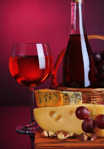 Vin rose, raisins et fromage sur fond coloré — Photo